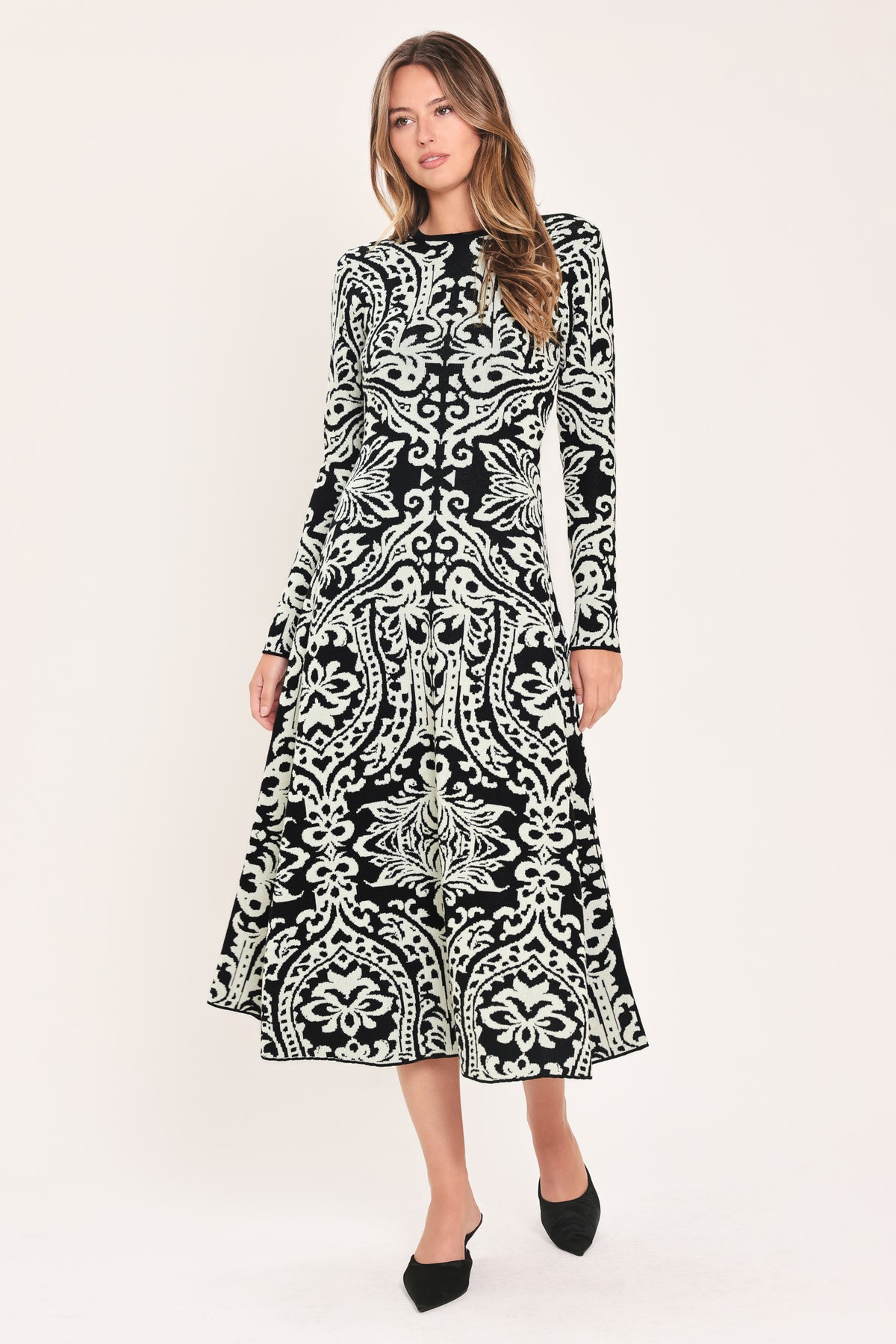 A woman modeling a long-sleeve midi dress with an intricate black and white damask pattern | Flying Tomato