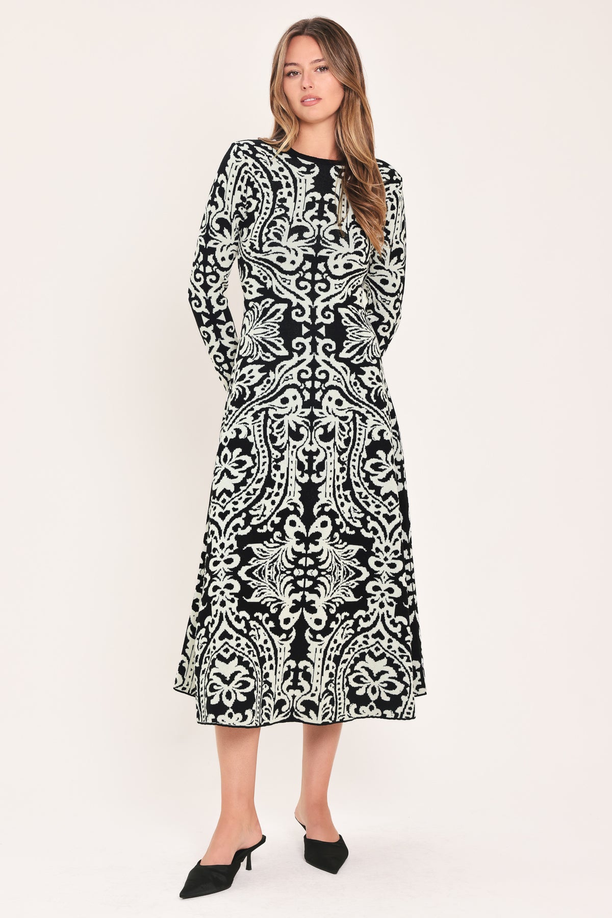 A woman modeling a long-sleeve midi dress with an intricate black and white damask pattern | Flying Tomato