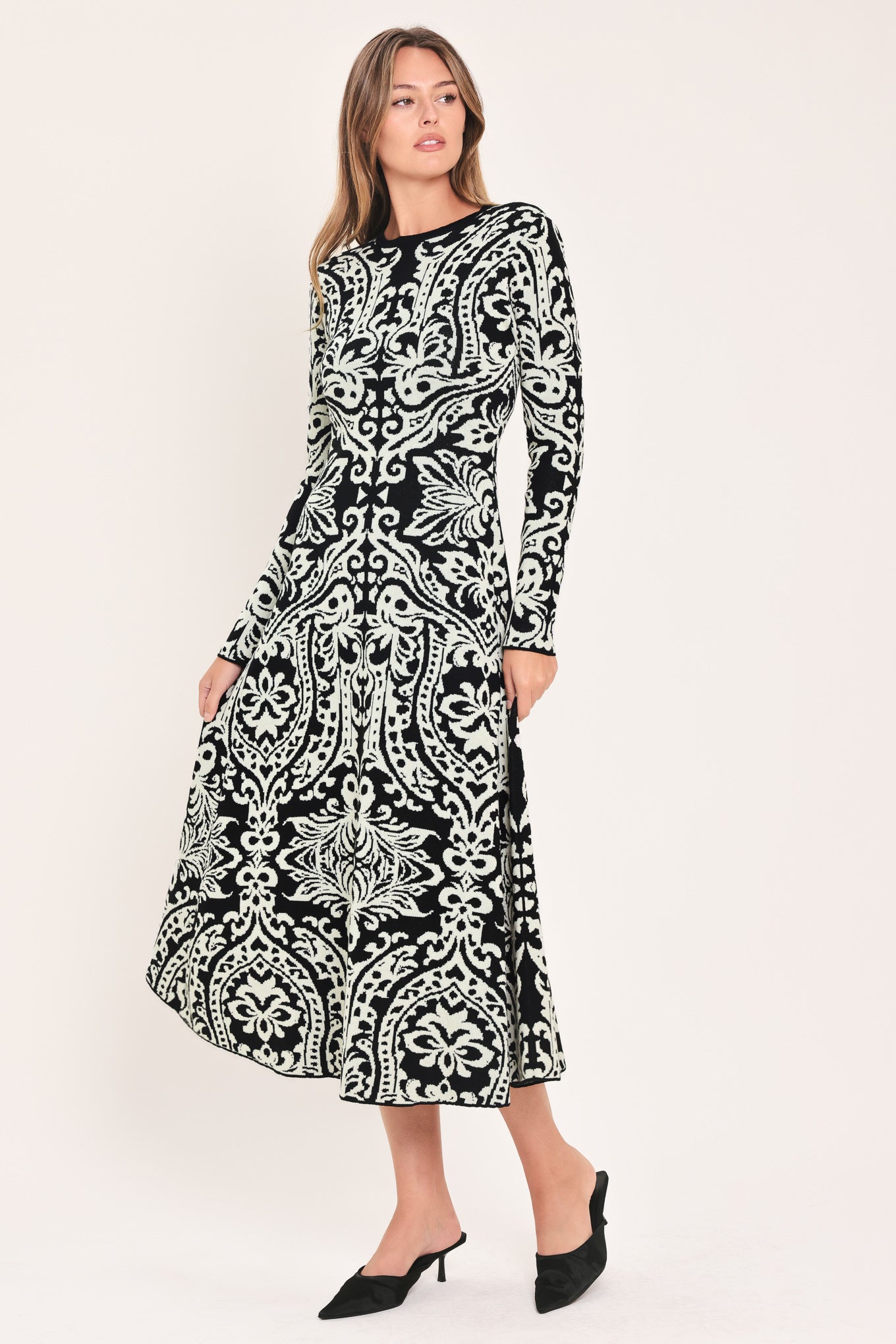 A woman modeling a long-sleeve midi dress with an intricate black and white damask pattern | Flying Tomato