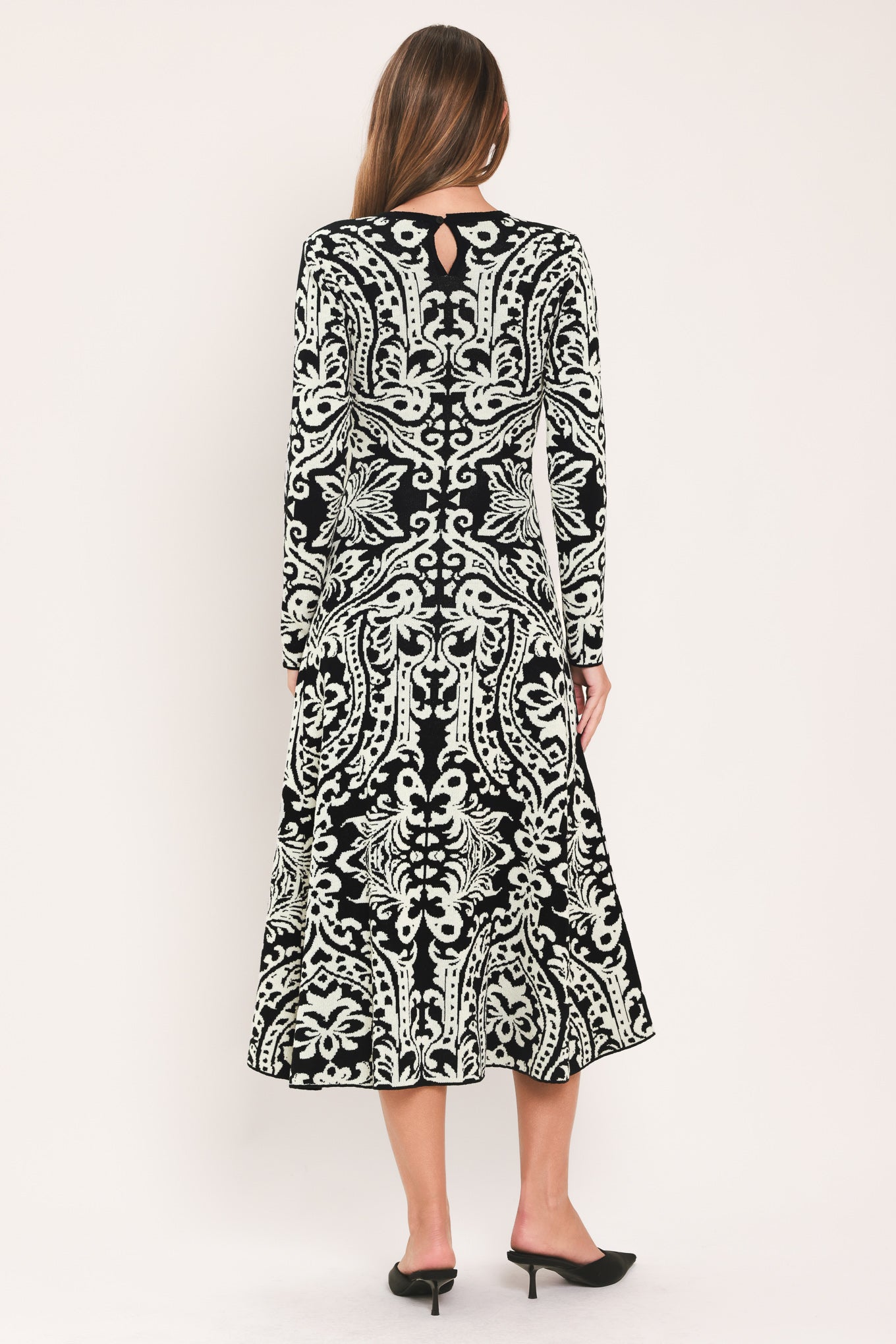 A woman modeling a long-sleeve midi dress with an intricate black and white damask pattern | Flying Tomato