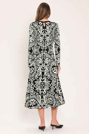 A woman modeling a long-sleeve midi dress with an intricate black and white damask pattern | Flying Tomato