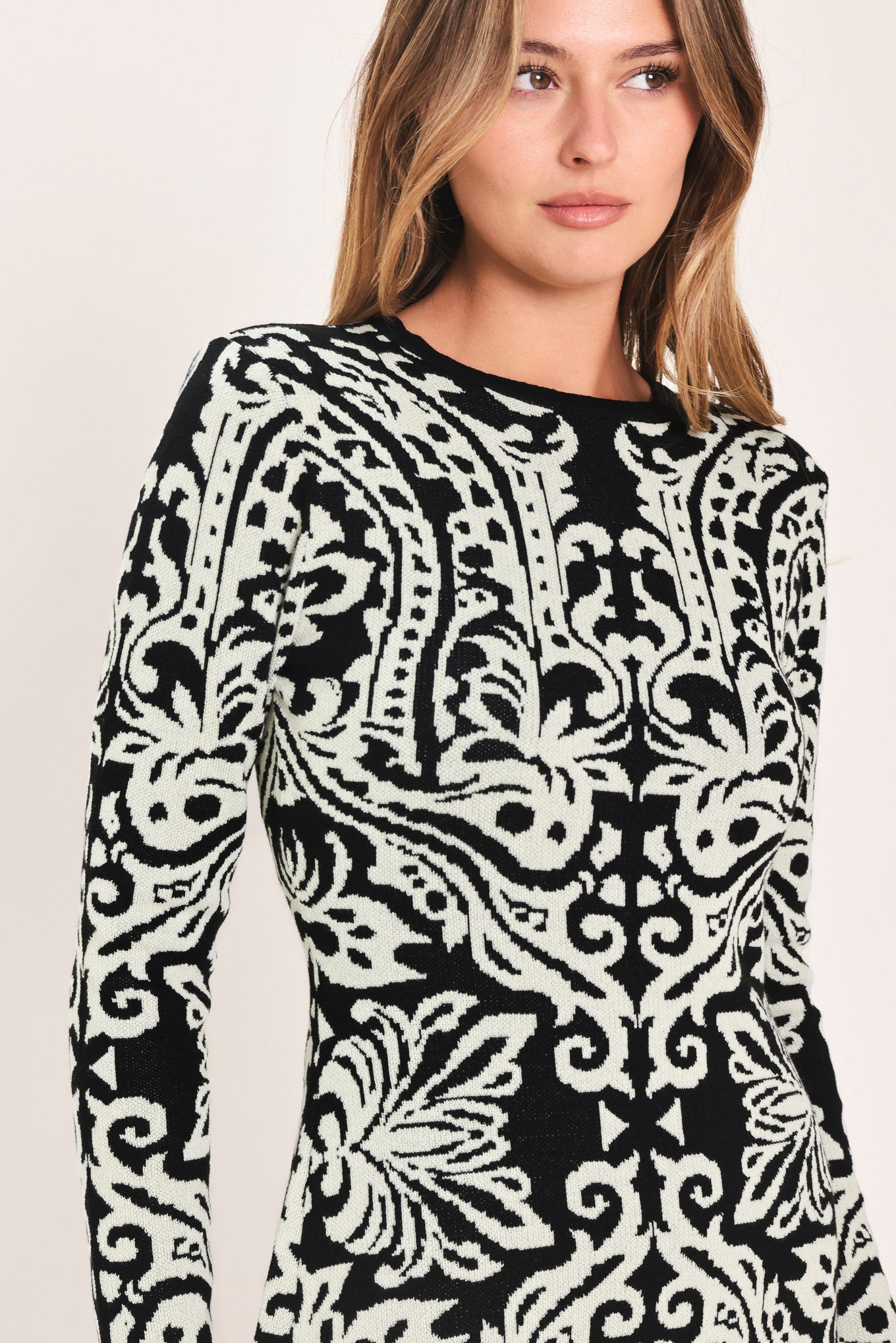 A woman modeling a long-sleeve midi dress with an intricate black and white damask pattern | Flying Tomato