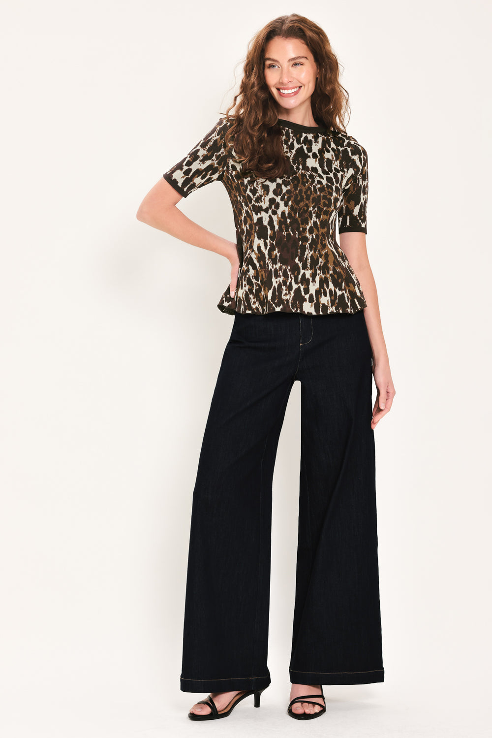 Woman wearing a short sleeve leopard print knitted sweater top with round neckline and peplum waist | Flying Tomato