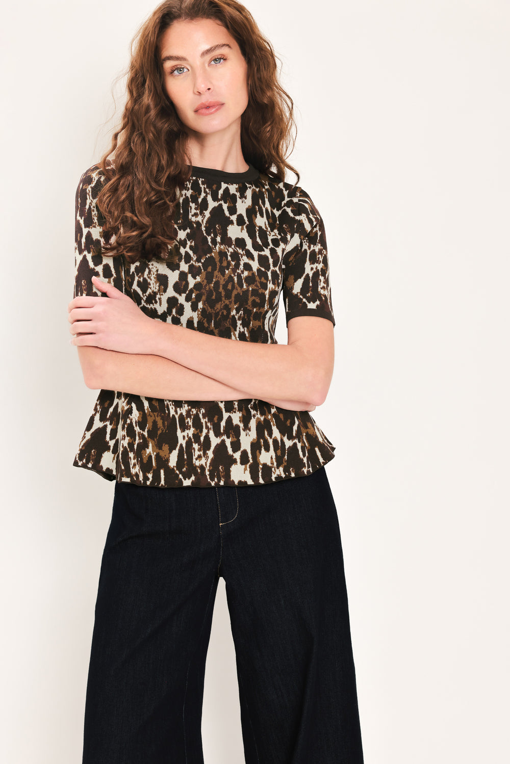 Woman wearing a short sleeve leopard print knitted sweater top with round neckline and peplum waist | Flying Tomato