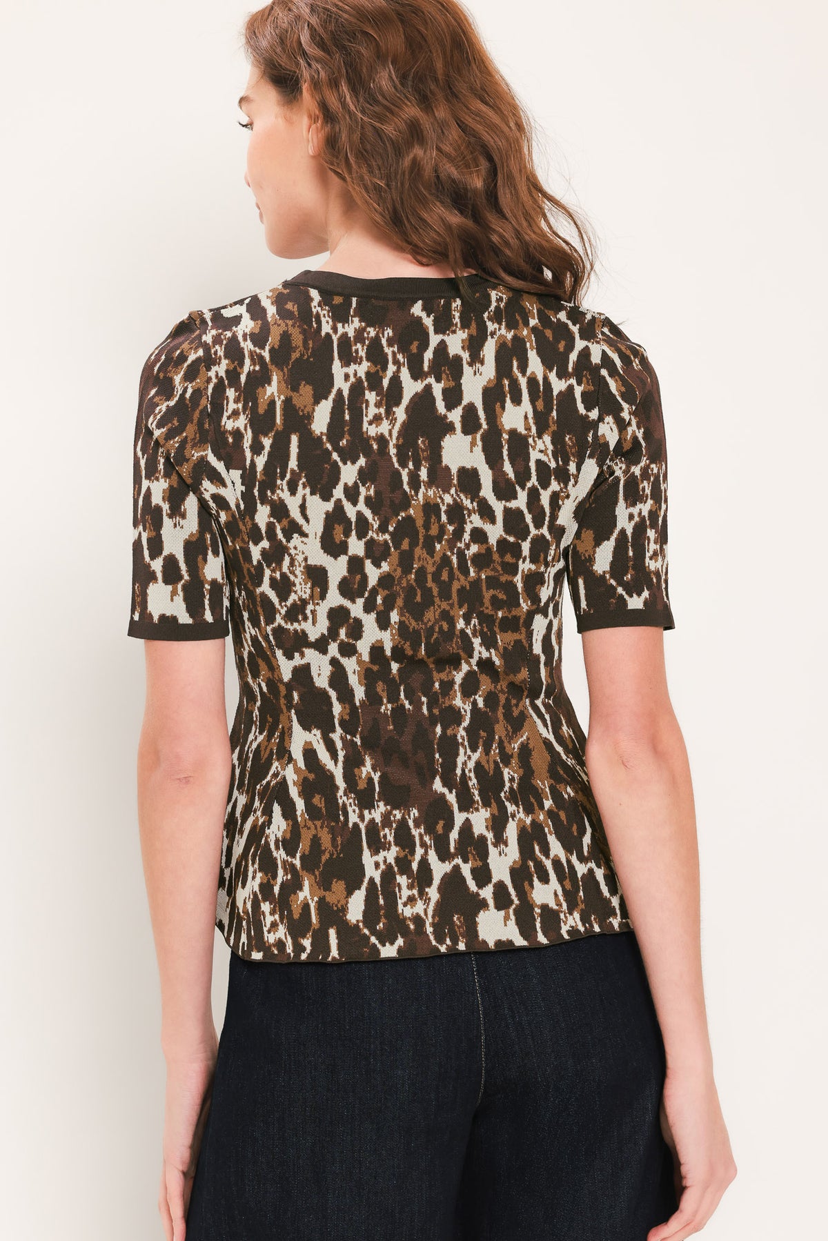 Woman wearing a short sleeve leopard print knitted sweater top with round neckline and peplum waist | Flying Tomato