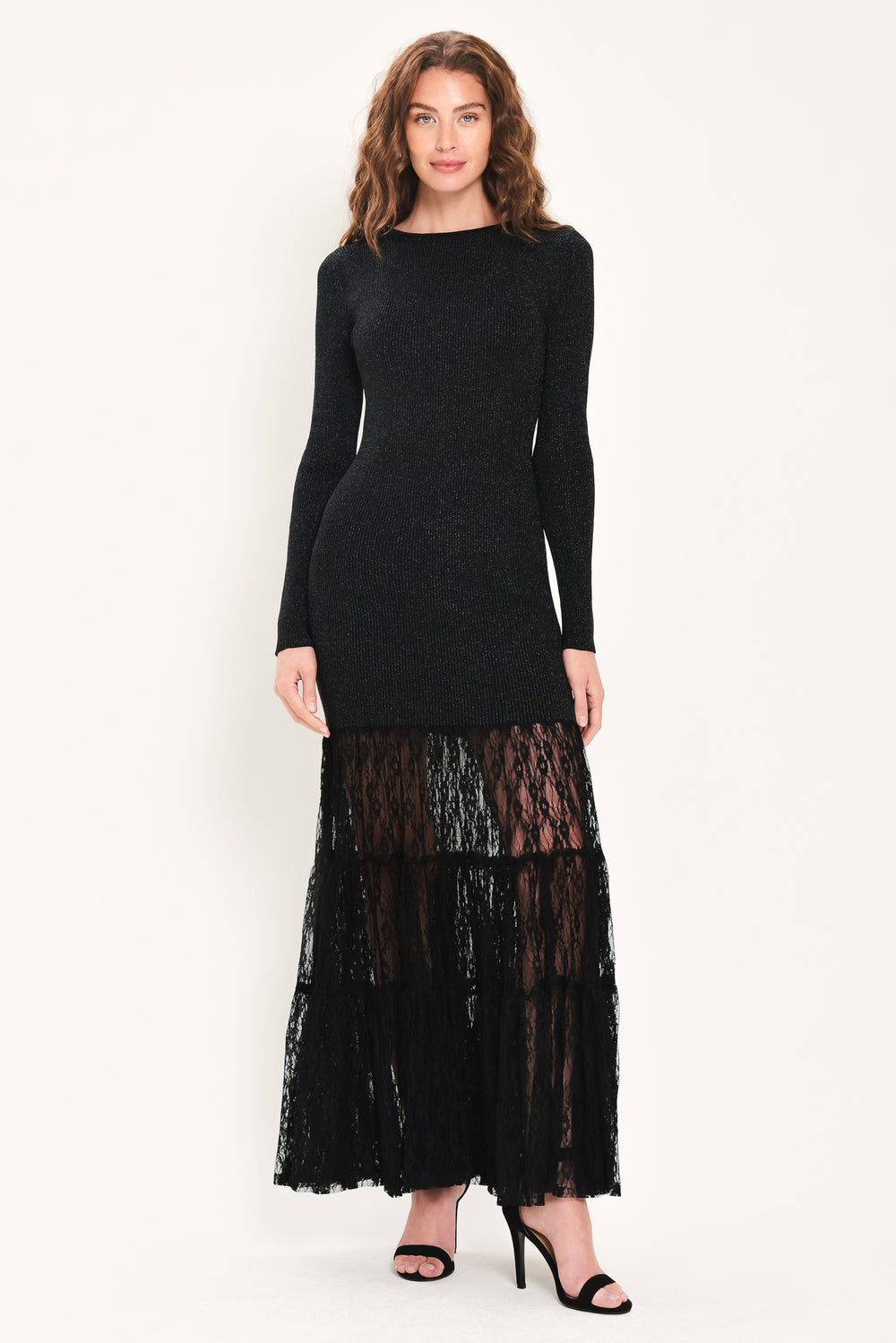 Woman wearing a long sleeve black sweater knit maxi dress but the sweater portion stops at the thighs and the bottom of the dress is tiered lace | Flying Tomato
