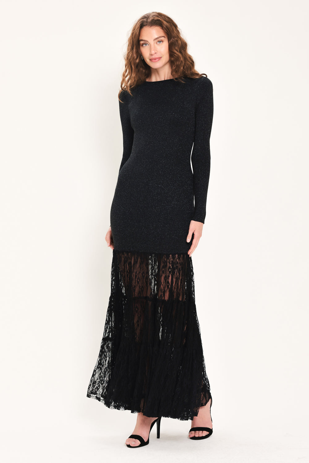 Woman wearing a long sleeve black sweater knit maxi dress but the sweater portion stops at the thighs and the bottom of the dress is tiered lace | Flying Tomato