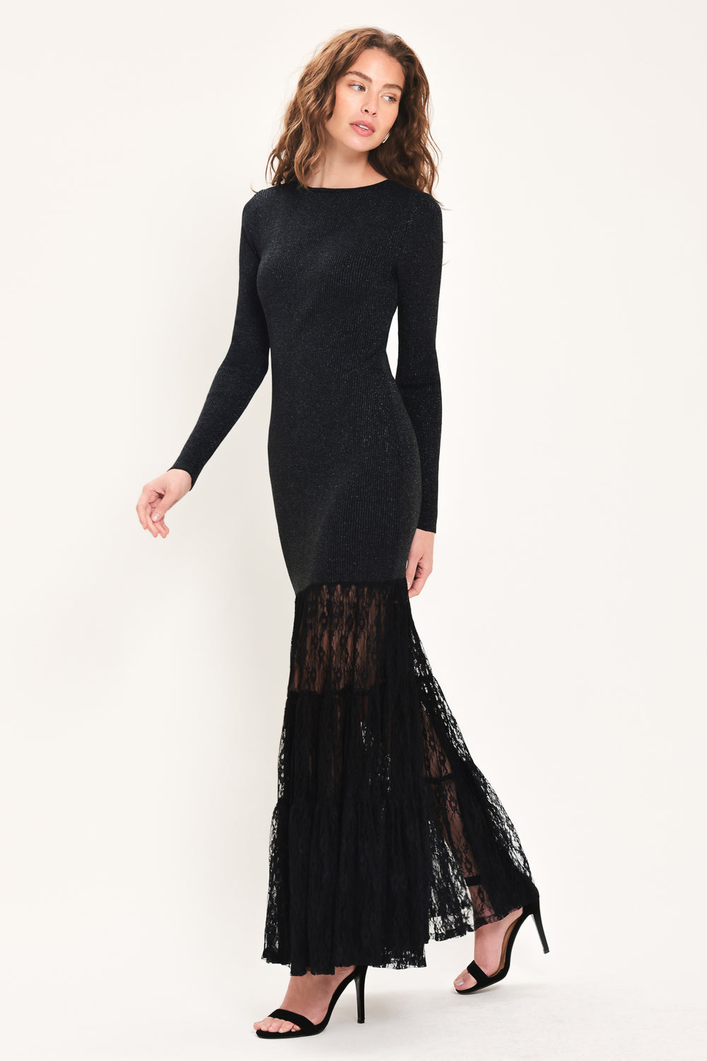 Woman wearing a long sleeve black sweater knit maxi dress but the sweater portion stops at the thighs and the bottom of the dress is tiered lace | Flying Tomato