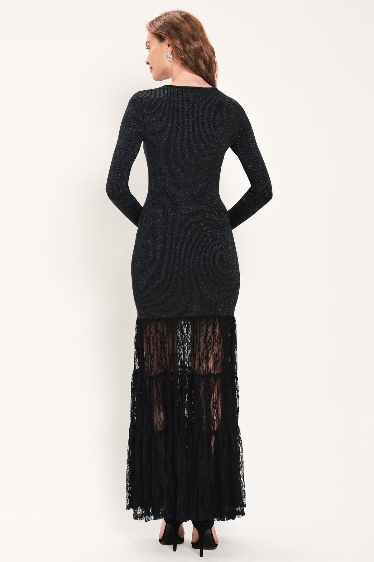 Woman wearing a long sleeve black sweater knit maxi dress but the sweater portion stops at the thighs and the bottom of the dress is tiered lace | Flying Tomato