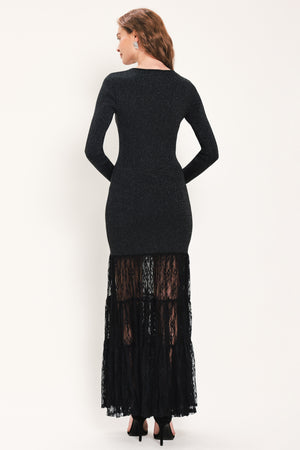 Woman wearing a long sleeve black sweater knit maxi dress but the sweater portion stops at the thighs and the bottom of the dress is tiered lace | Flying Tomato