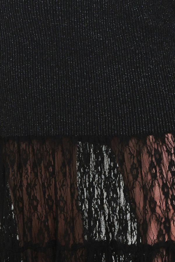 Woman wearing a long sleeve black sweater knit maxi dress but the sweater portion stops at the thighs and the bottom of the dress is tiered lace | Flying Tomato