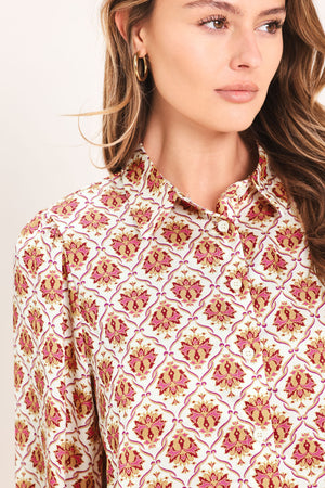 Woman wearing a burgundy long sleeve printed woven top featuring collar and button down | Flying Tomato