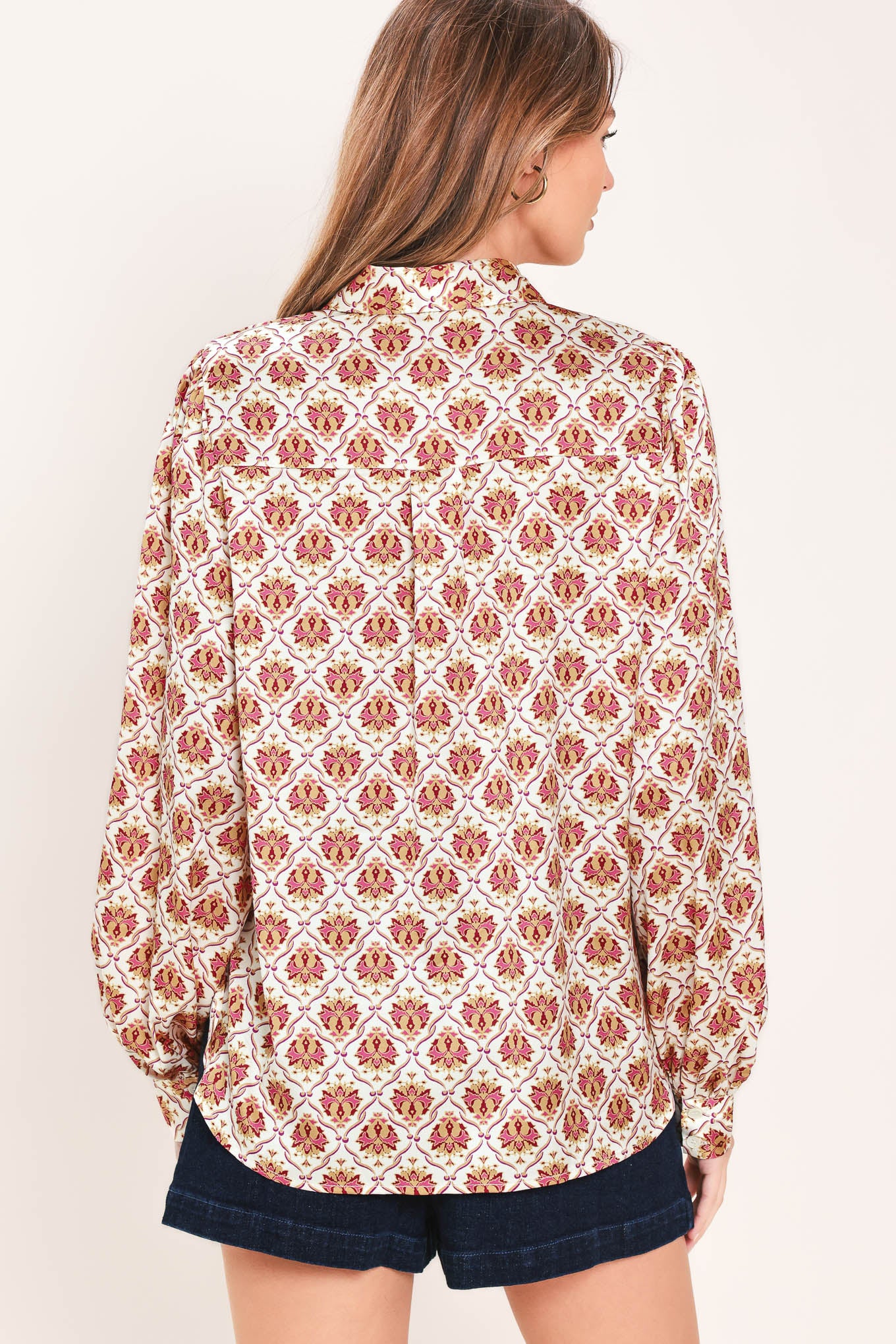 Woman wearing a burgundy long sleeve printed woven top featuring collar and button down | Flying Tomato