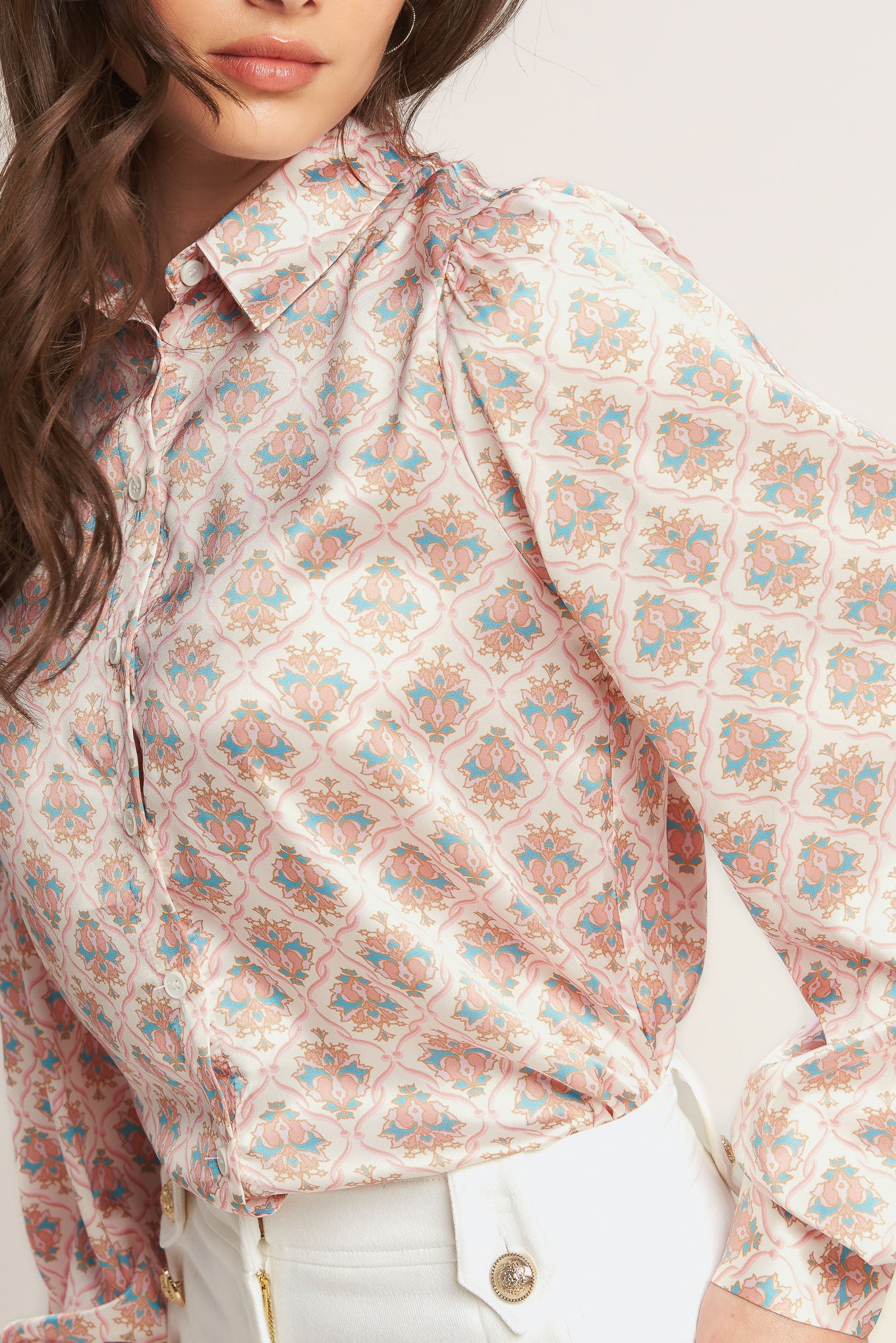 Woman wearing a floral blouse and white pants against a plain background - Flying Tomato