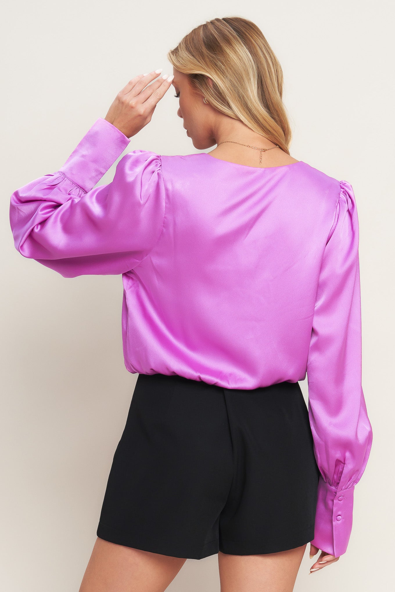 A solid woven top featuring surplice neckline, long sleeve with cuff and elasticized waist