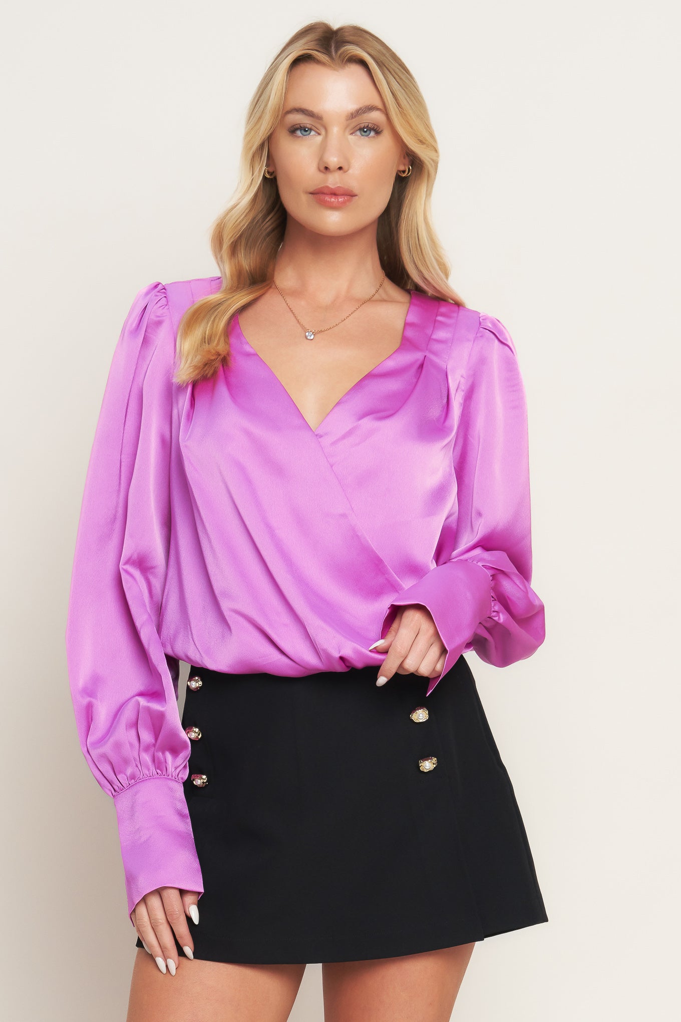 A solid woven top featuring surplice neckline, long sleeve with cuff and elasticized waist