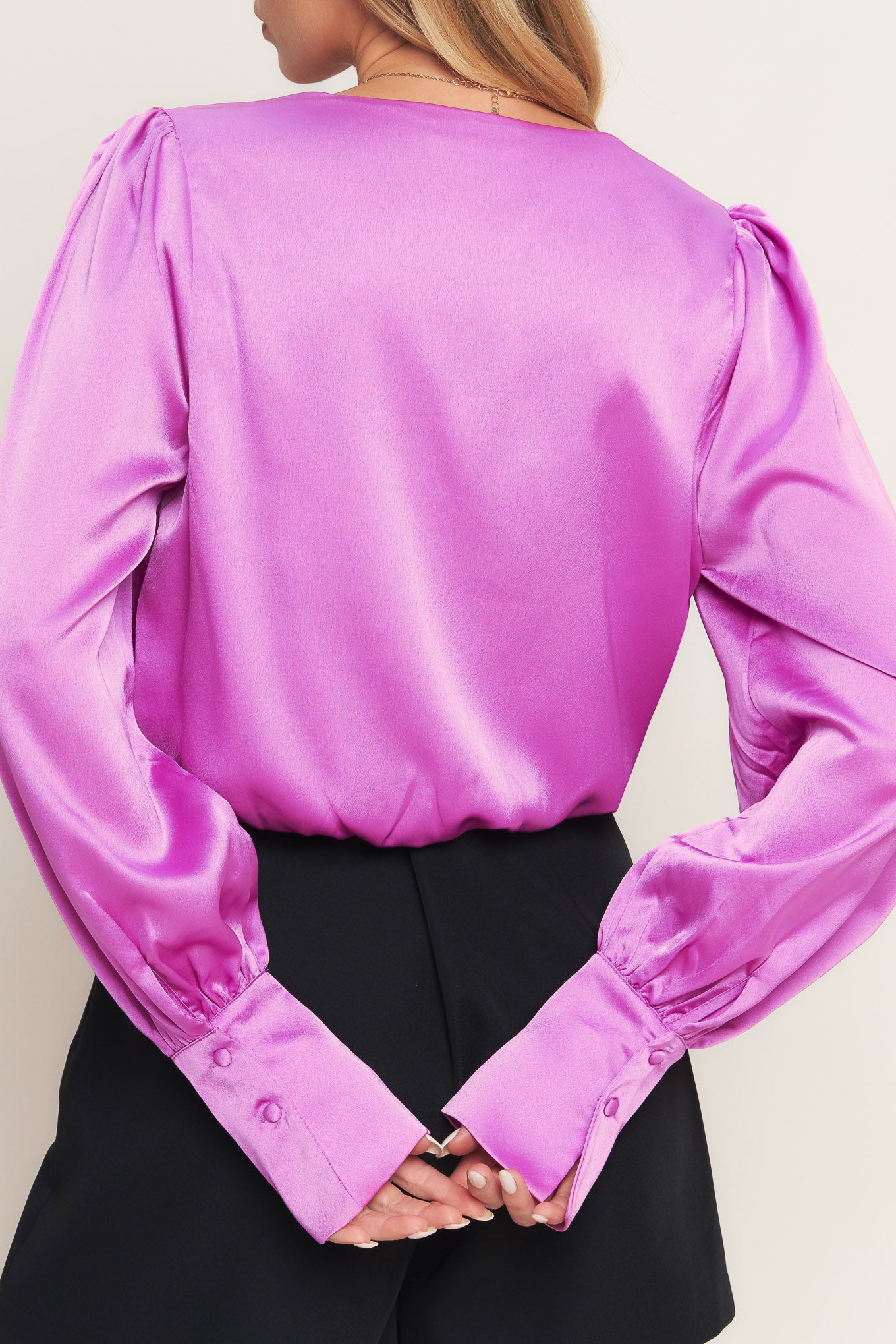 A solid woven top featuring surplice neckline, long sleeve with cuff and elasticized waist