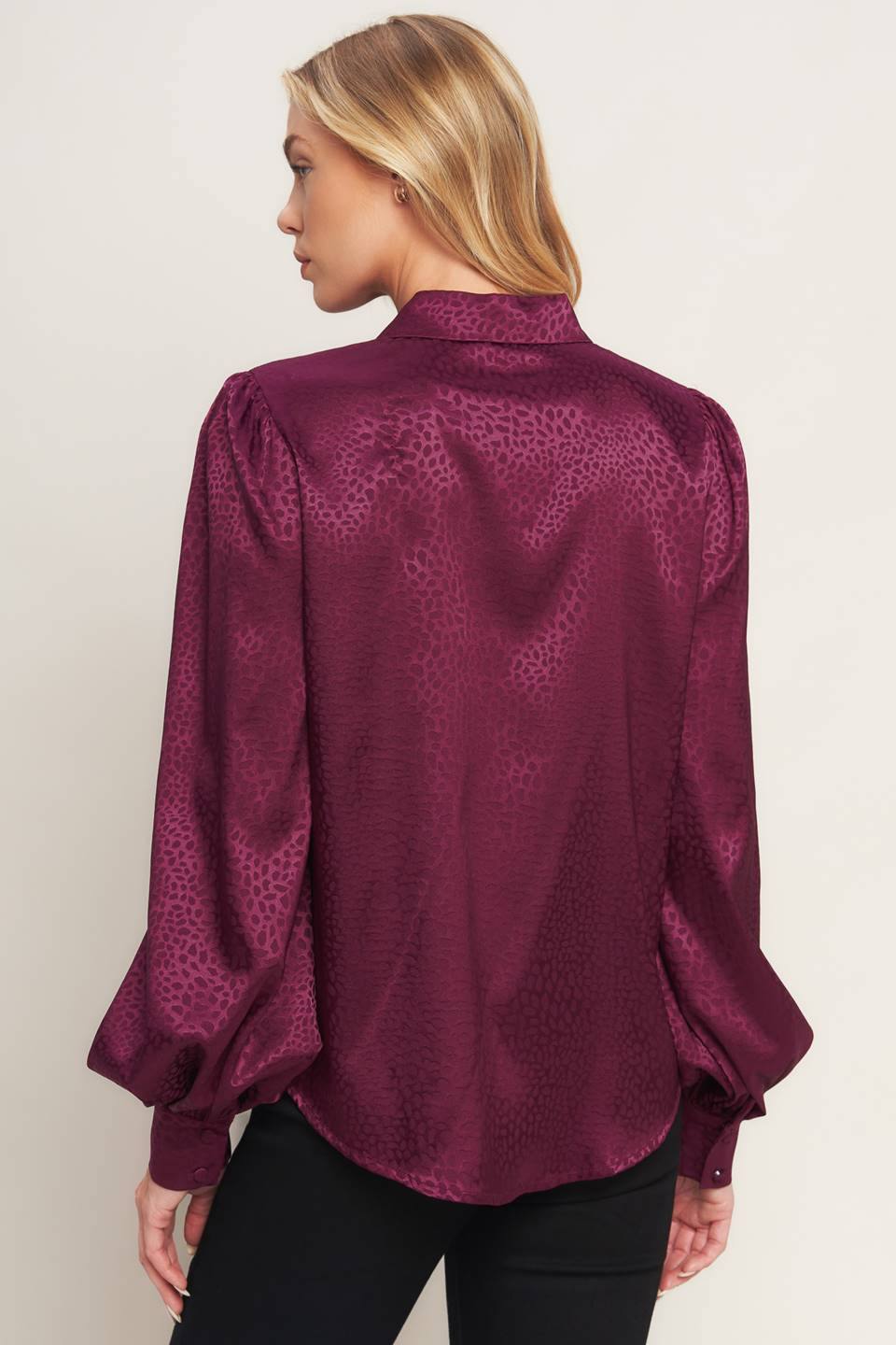 A solid woven top featuring shirt collar, jewel button down, long puff sleeve and cuff