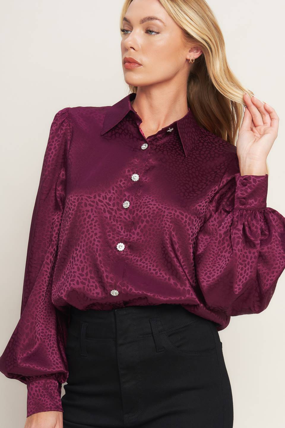 A solid woven top featuring shirt collar, jewel button down, long puff sleeve and cuff