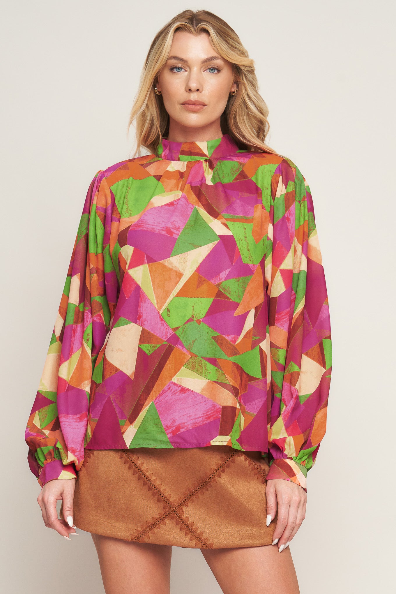 A printed woven top featuring high neckline, wide long sleeve with cuff and back neck button closure