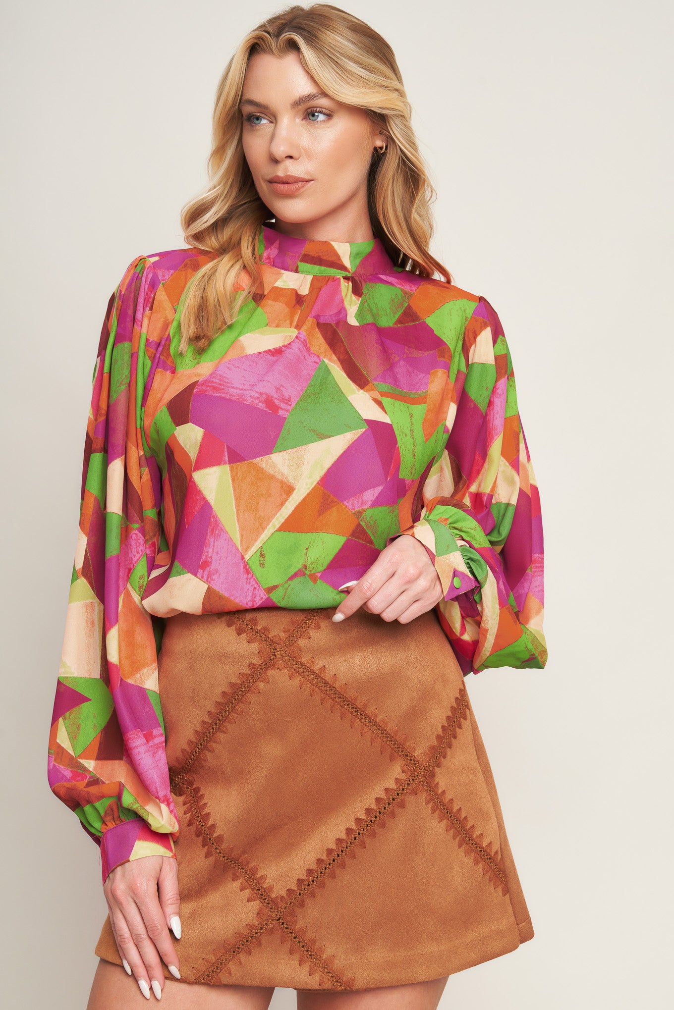 A printed woven top featuring high neckline, wide long sleeve with cuff and back neck button closure