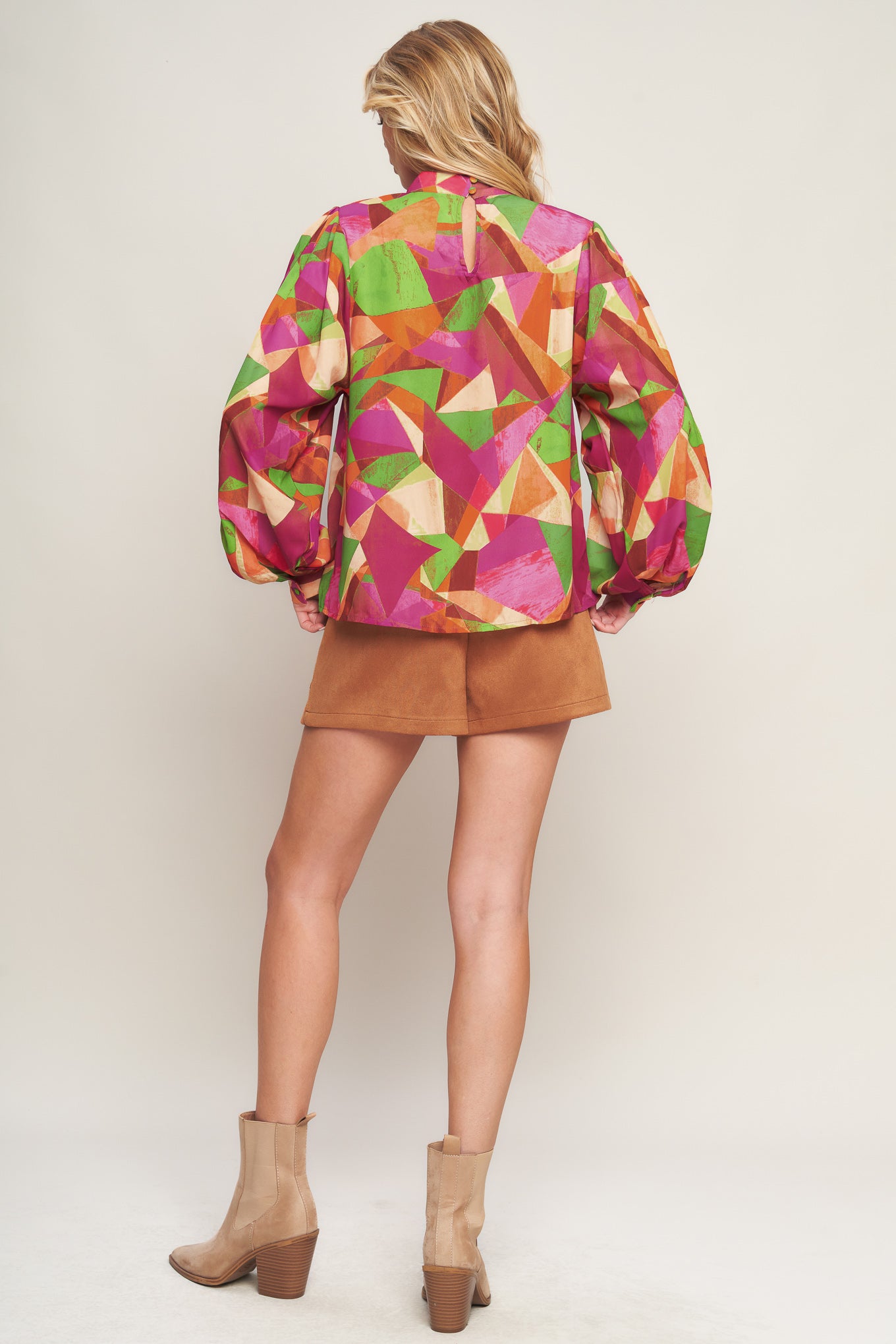 A printed woven top featuring high neckline, wide long sleeve with cuff and back neck button closure