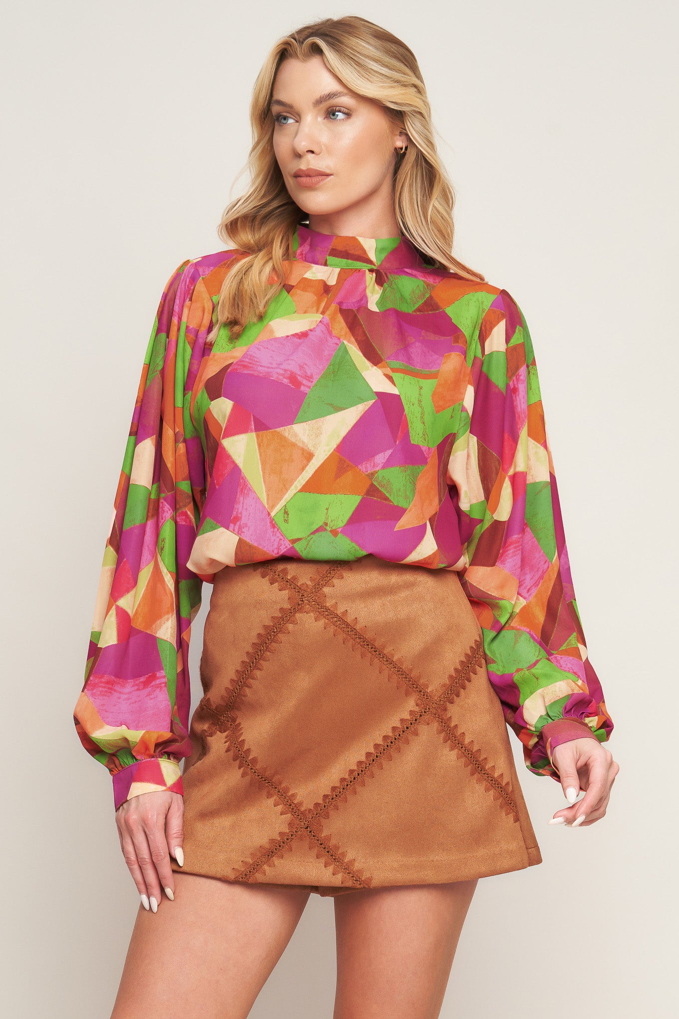 A printed woven top featuring high neckline, wide long sleeve with cuff and back neck button closure