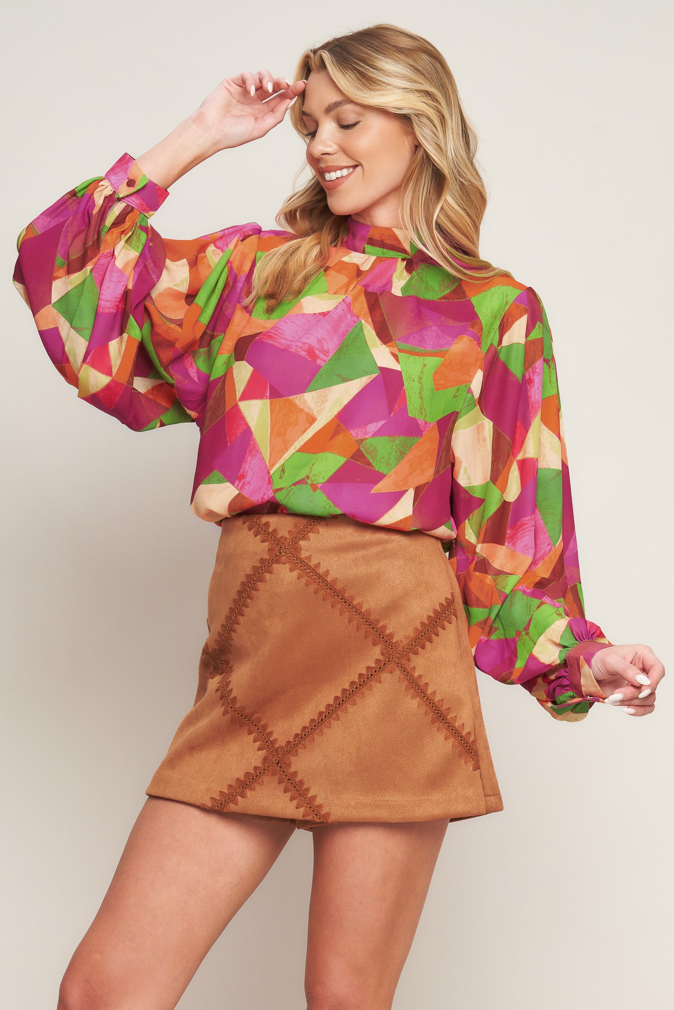 A printed woven top featuring high neckline, wide long sleeve with cuff and back neck button closure