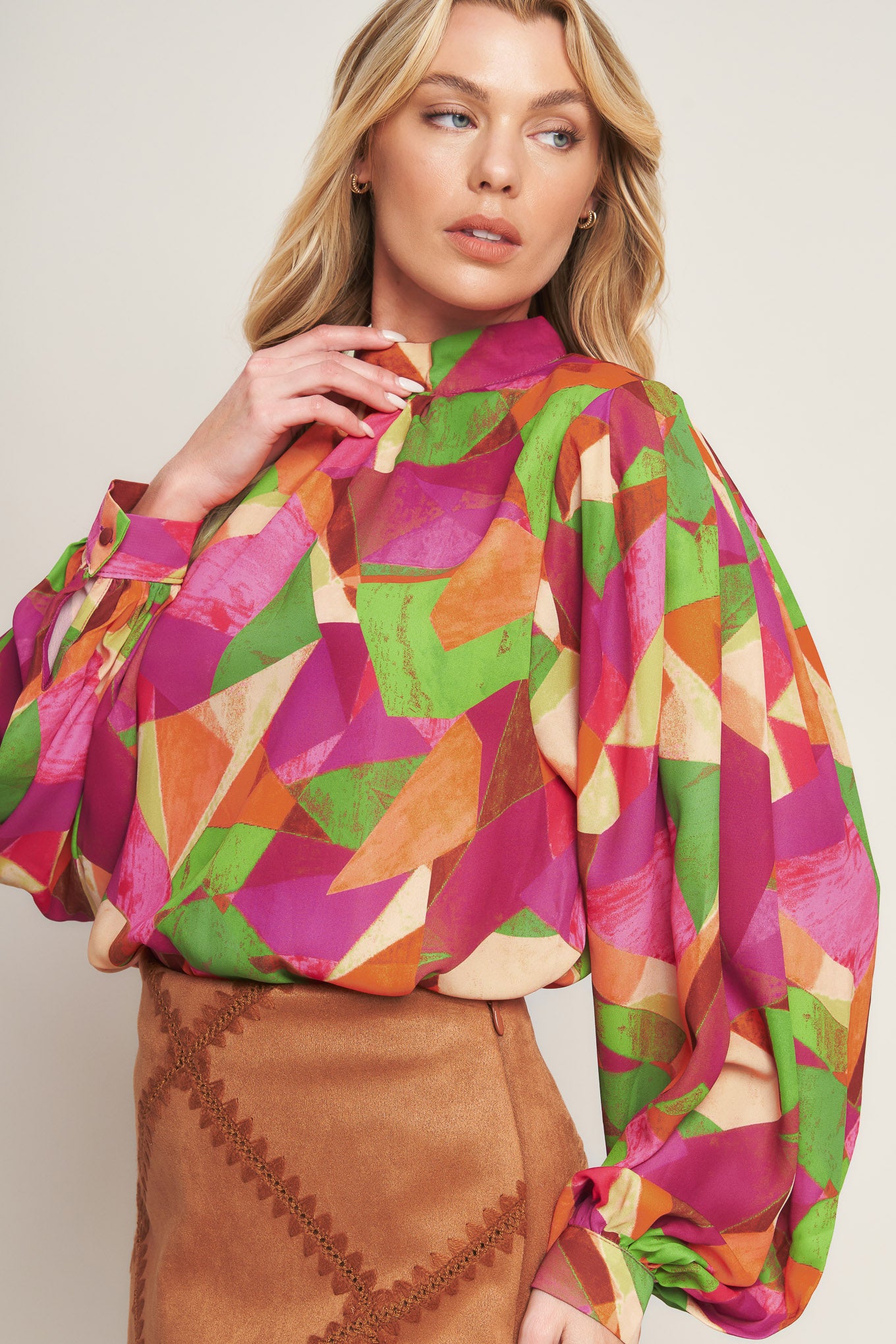 A printed woven top featuring high neckline, wide long sleeve with cuff and back neck button closure
