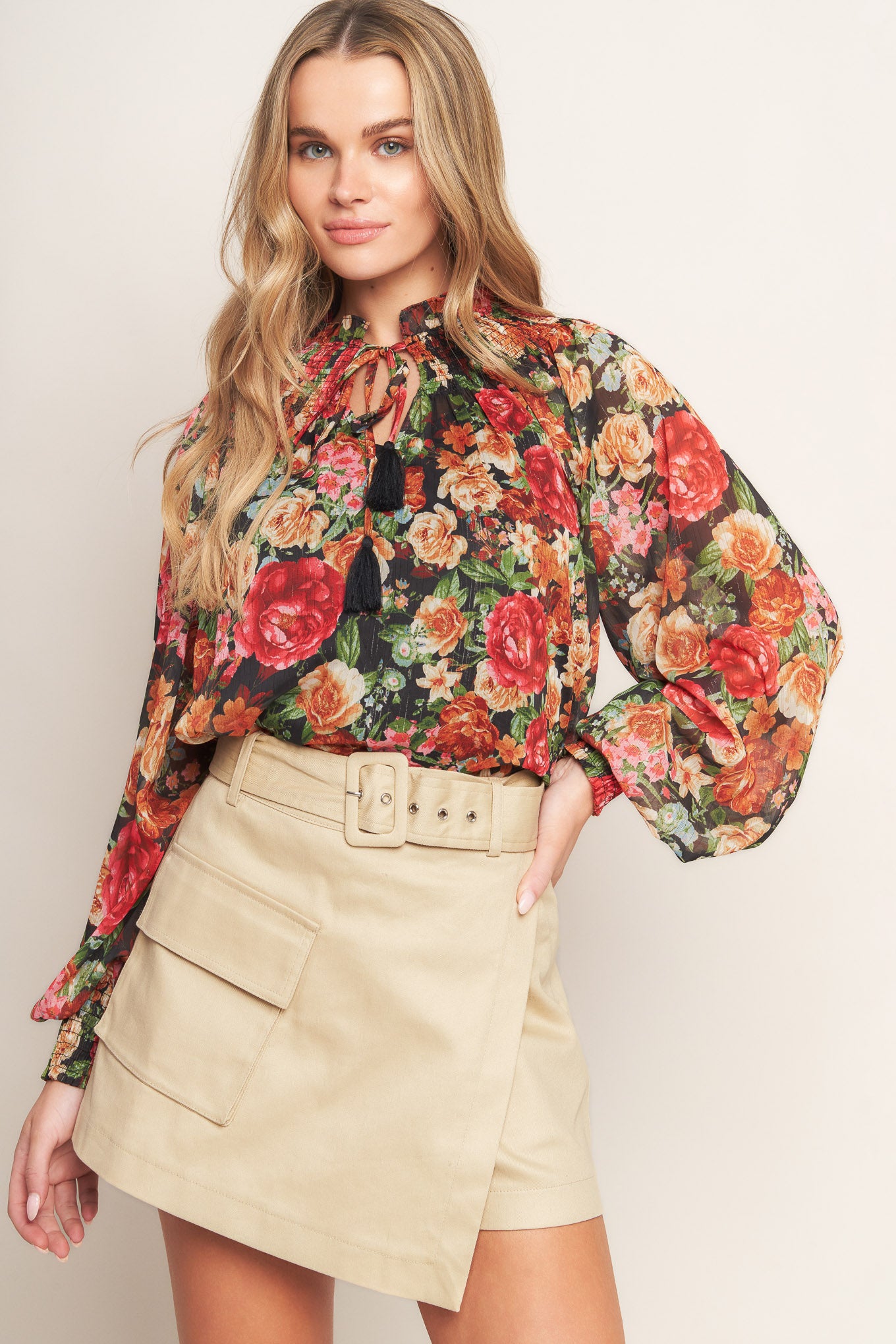 A printed woven top featuring high neckline, peasant sleeve with smocked cuff and front tie detail