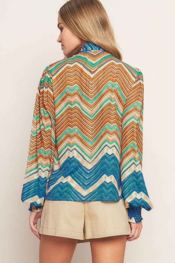 A printed woven top featuring high neckline with back neck tie and long sleeve with smocked cuff