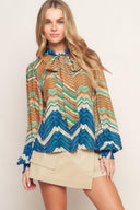A printed woven top featuring high neckline with back neck tie and long sleeve with smocked cuff