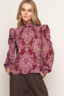 A printed woven top featuring high neckline, long puff sleeve and back neck tie closure