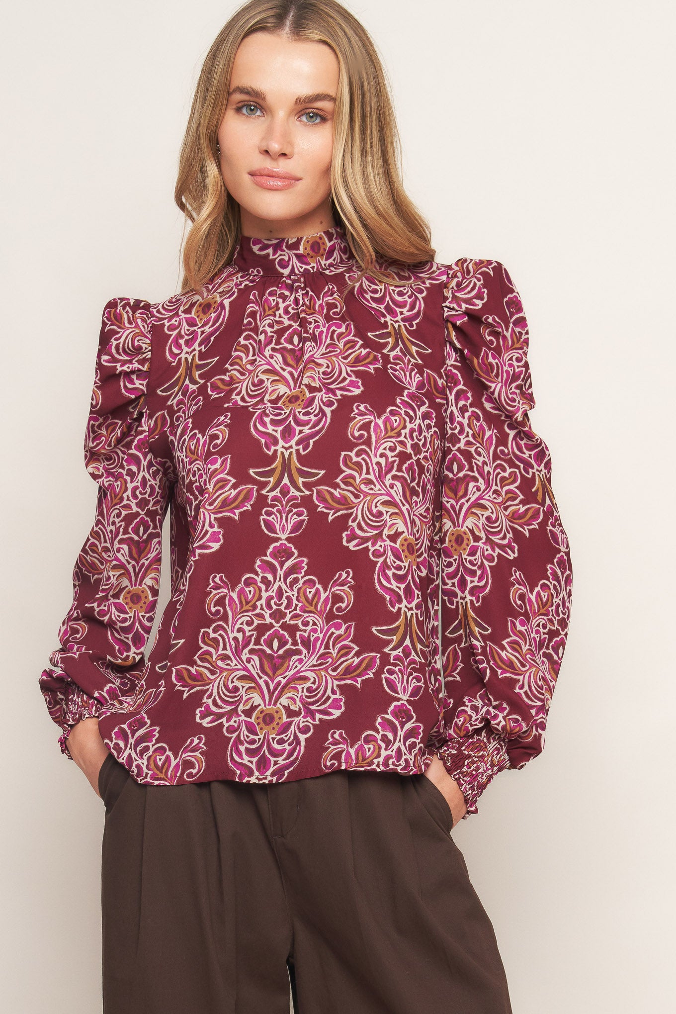 A printed woven top featuring high neckline, long puff sleeve and back neck tie closure