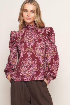 A printed woven top featuring high neckline, long puff sleeve and back neck tie closure