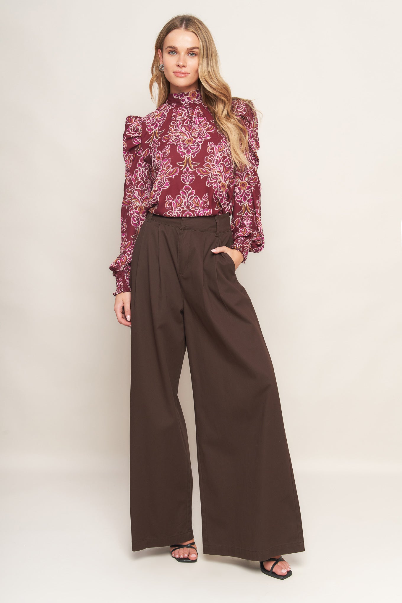 A printed woven top featuring high neckline, long puff sleeve and back neck tie closure