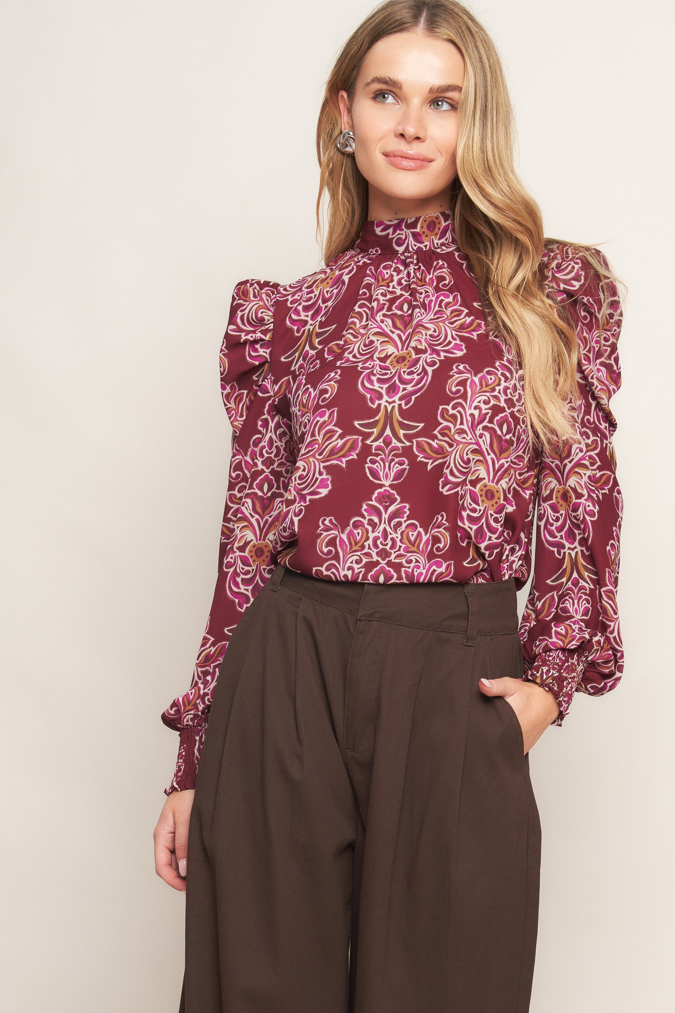 A printed woven top featuring high neckline, long puff sleeve and back neck tie closure