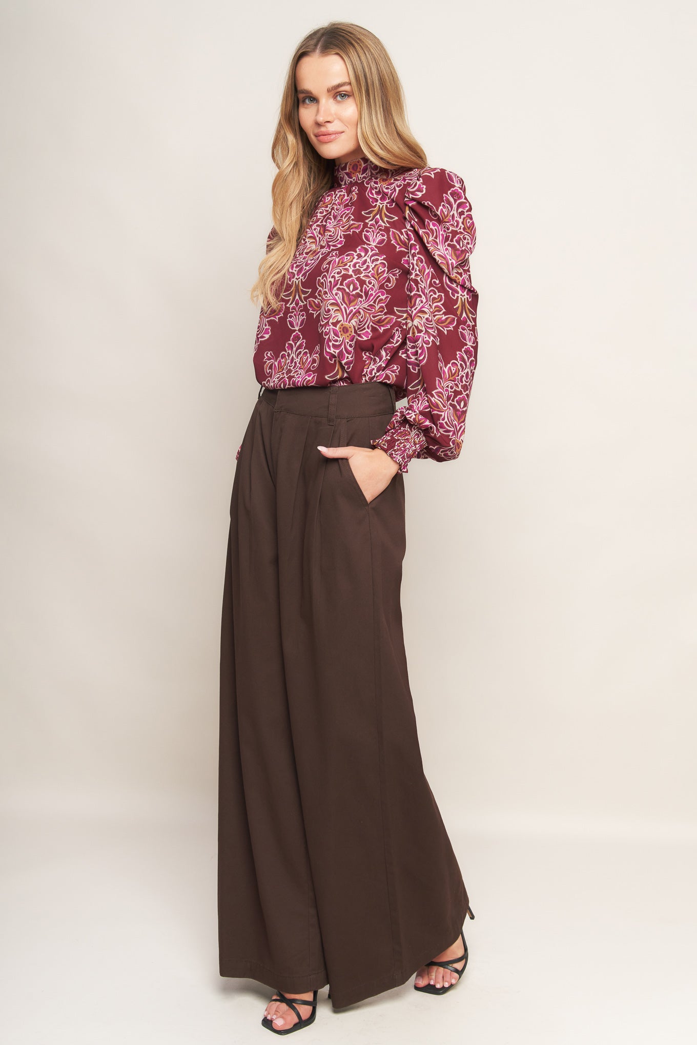 A printed woven top featuring high neckline, long puff sleeve and back neck tie closure