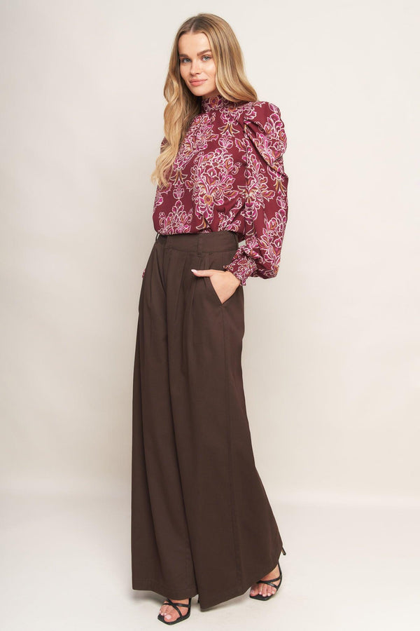 A printed woven top featuring high neckline, long puff sleeve and back neck tie closure
