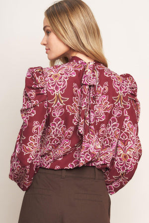 A printed woven top featuring high neckline, long puff sleeve and back neck tie closure