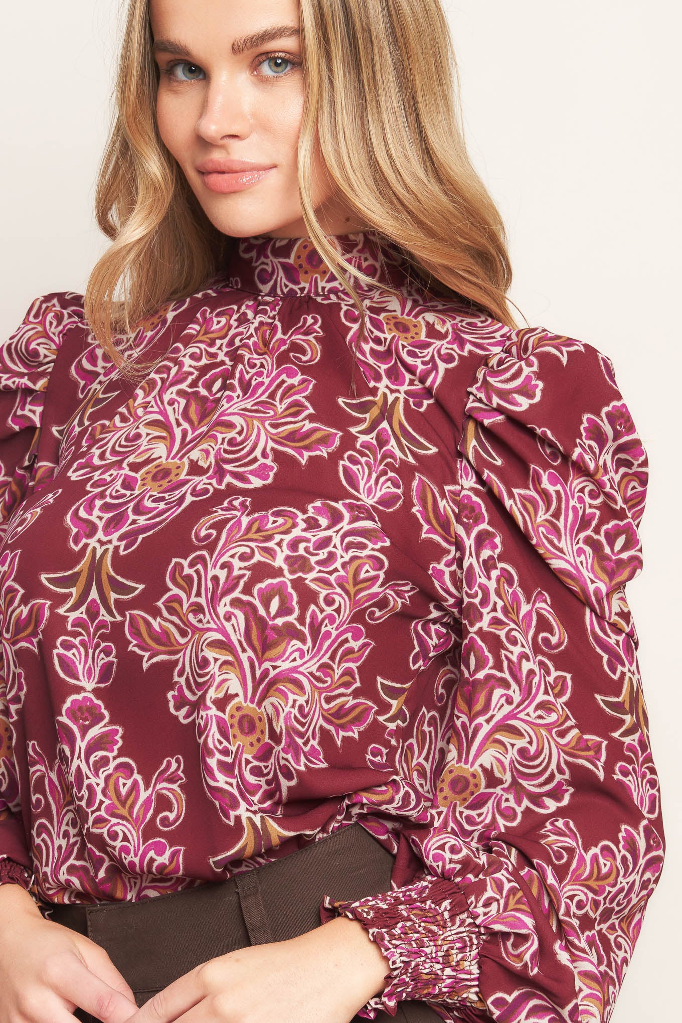 A printed woven top featuring high neckline, long puff sleeve and back neck tie closure