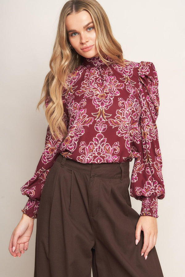 A printed woven top featuring high neckline, long puff sleeve and back neck tie closure