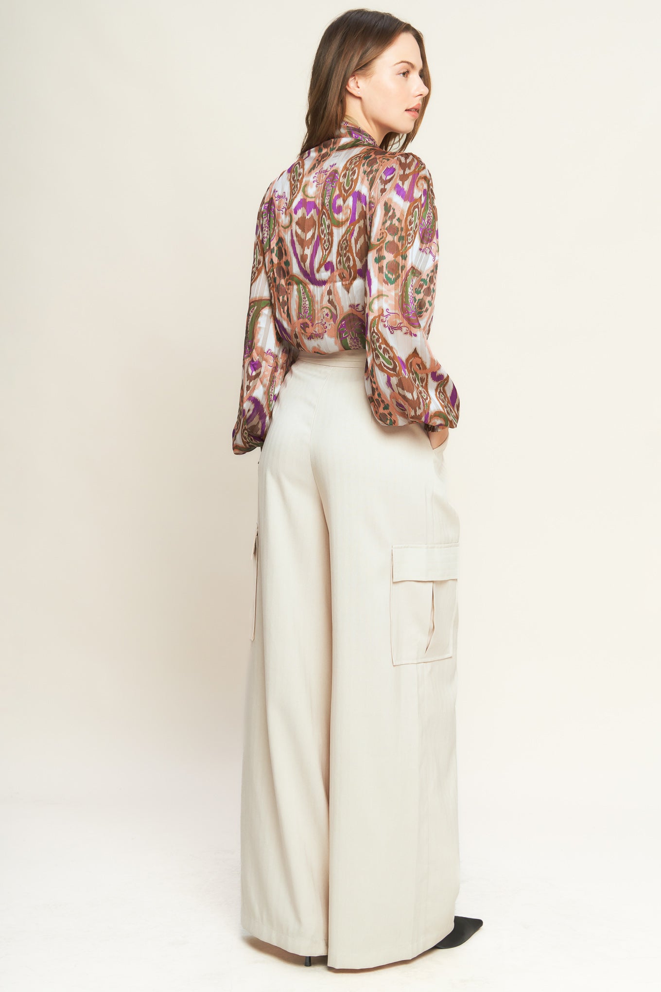 Woman wearing a patterned blouse with a bow tie against a plain background. A printed woven top featuring front bow tie and long sleeve with smocked cuff - FLYING TOMATO