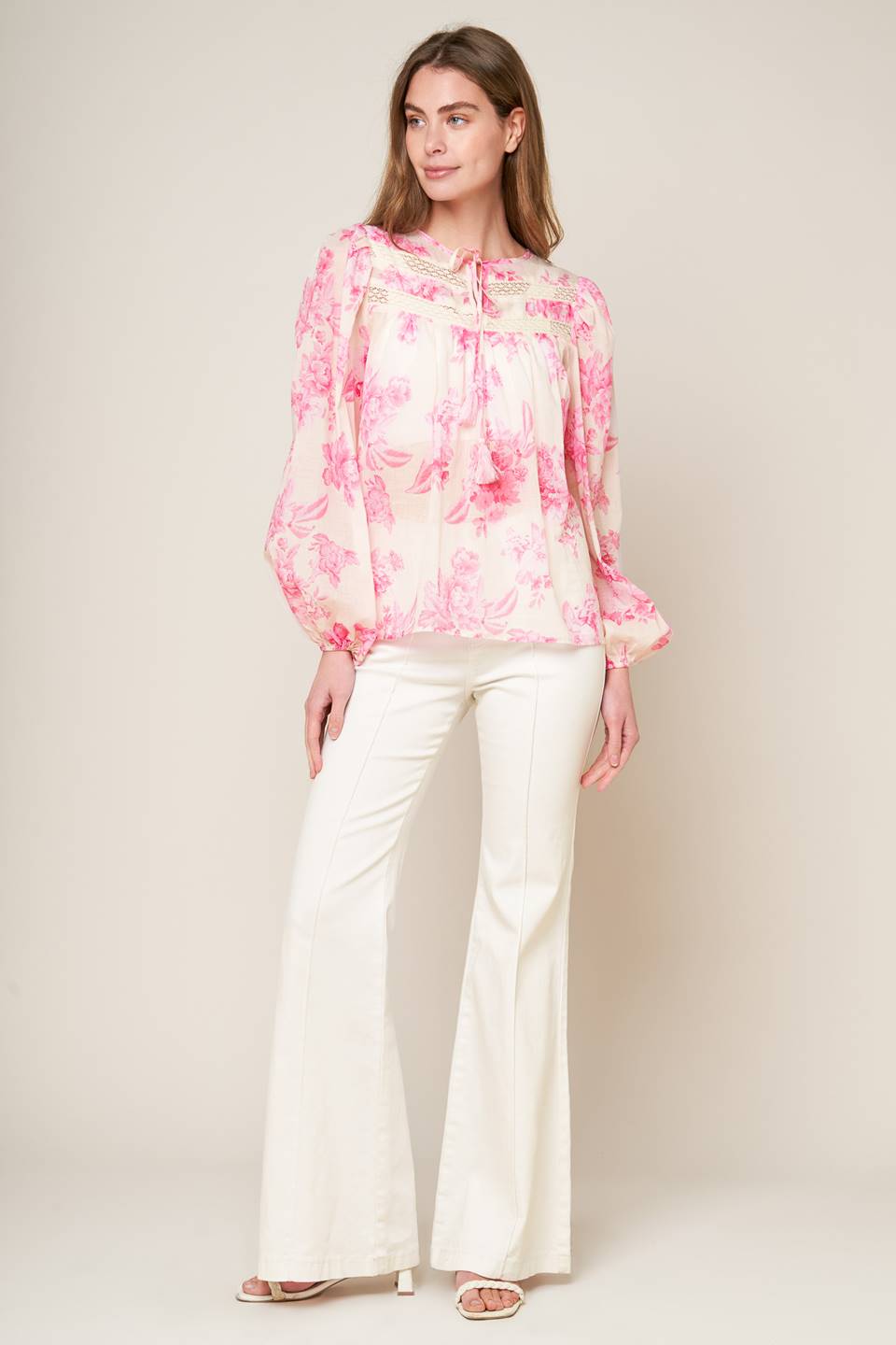 A printed woven peasant top featuring round neckline with tie/tassel, long sleeve and lace inset detail