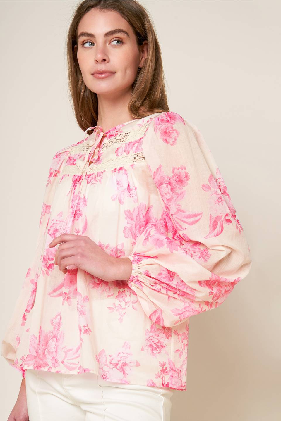 A printed woven peasant top featuring round neckline with tie/tassel, long sleeve and lace inset detail