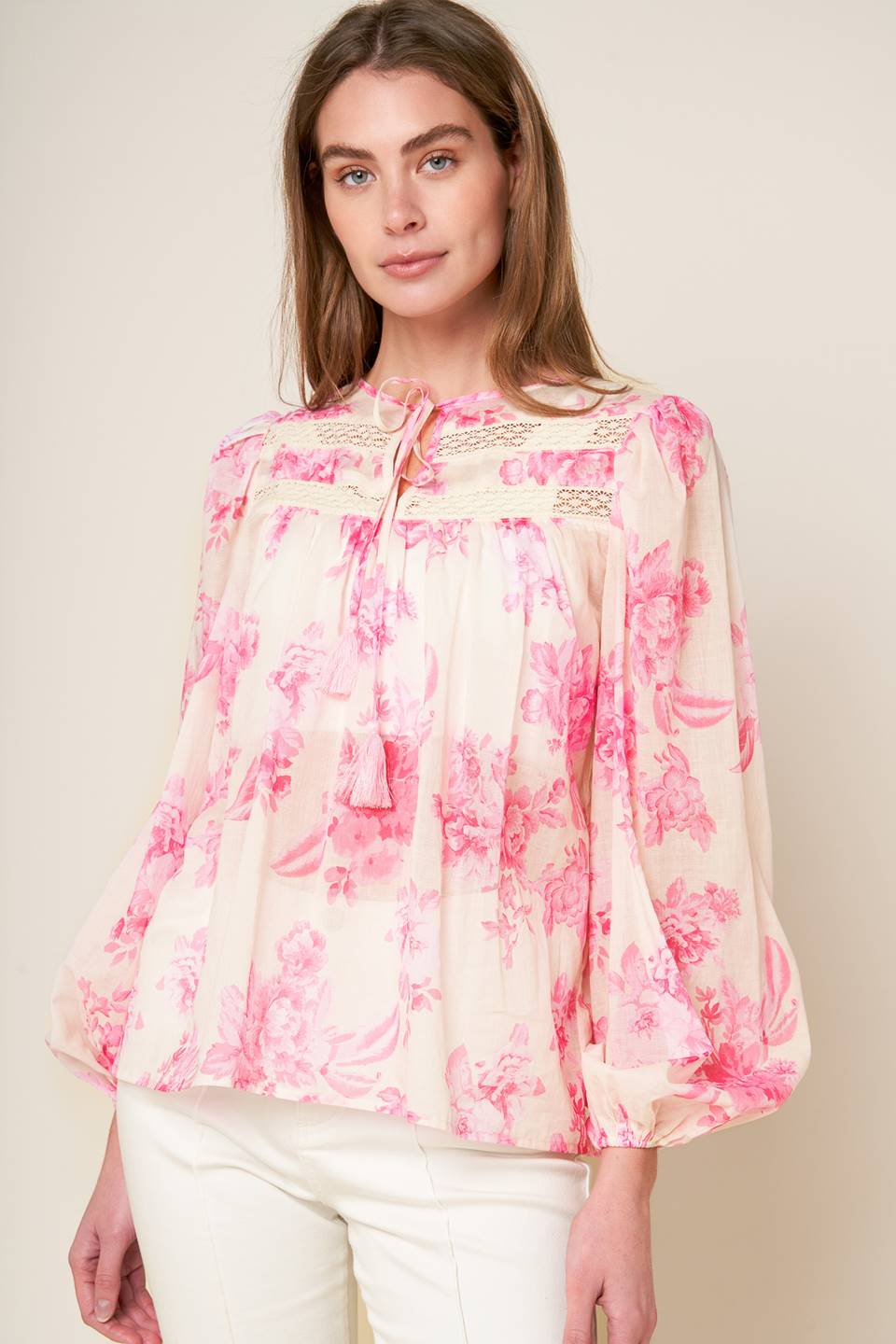 A printed woven peasant top featuring round neckline with tie/tassel, long sleeve and lace inset detail