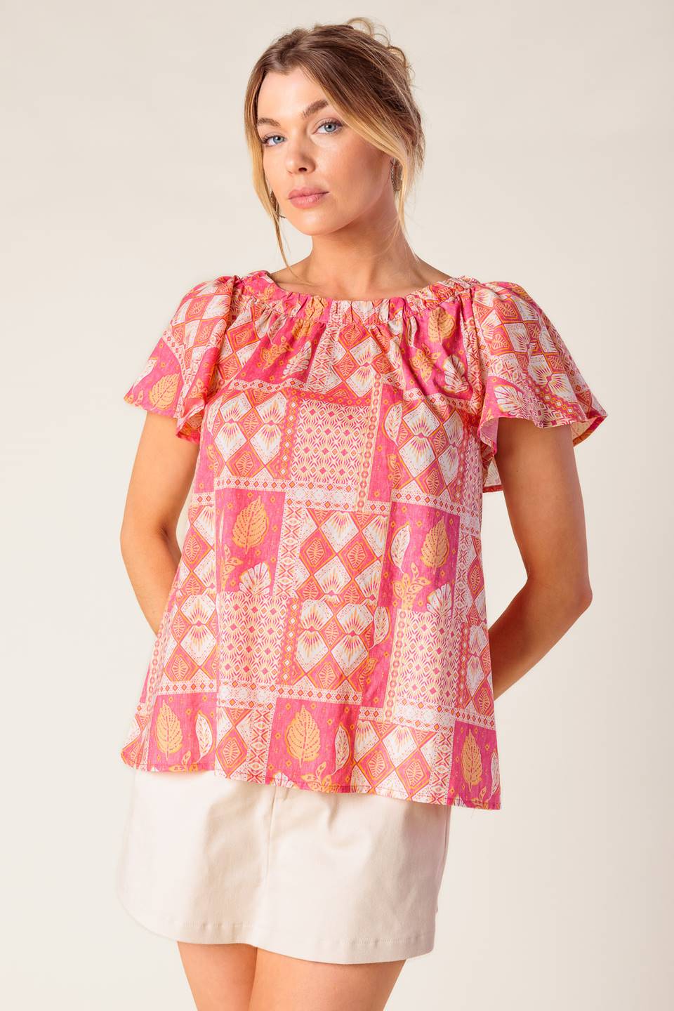 A printed woven top featuring round neckline, flutter sleeve and back neck button closure