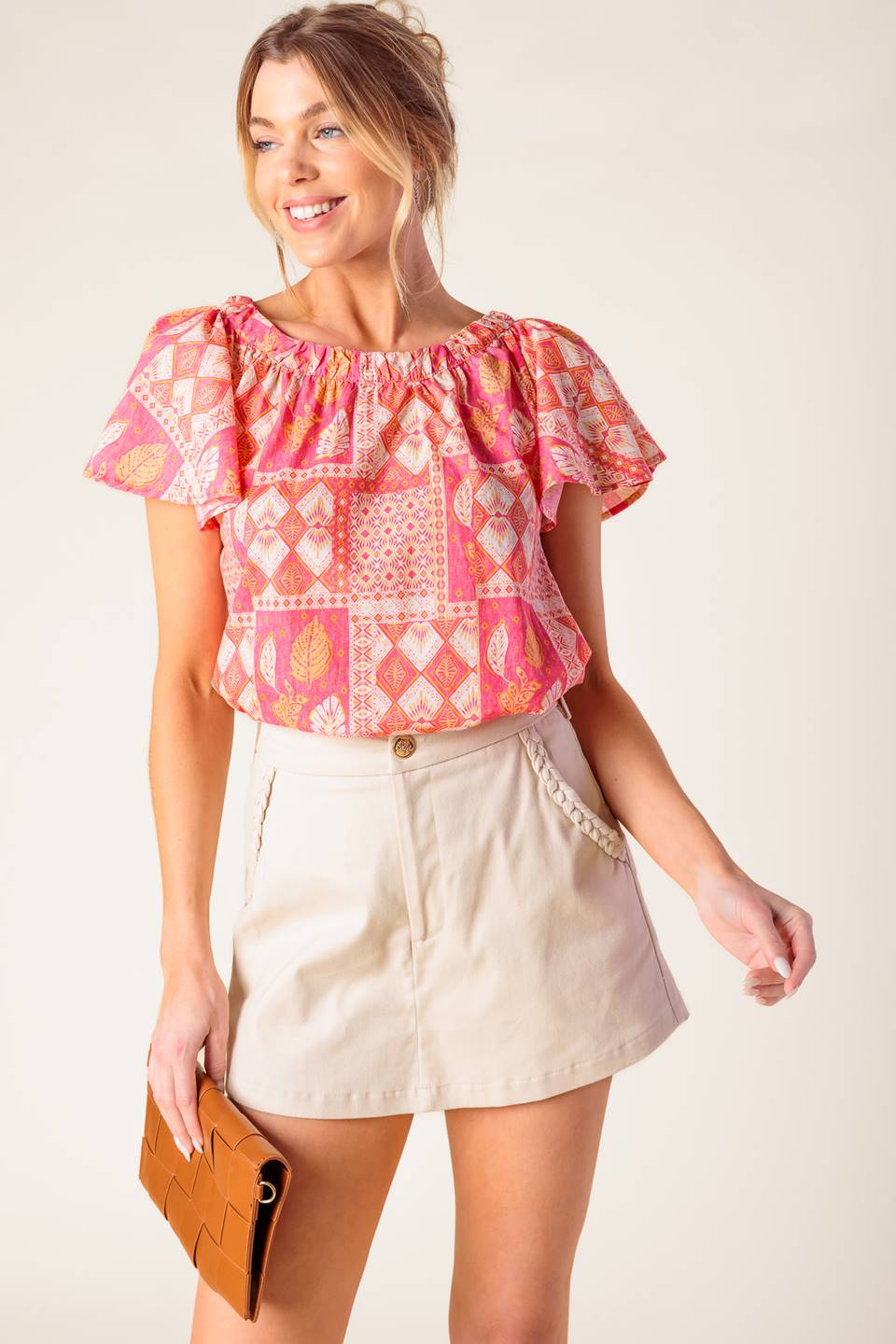 A printed woven top featuring round neckline, flutter sleeve and back neck button closure