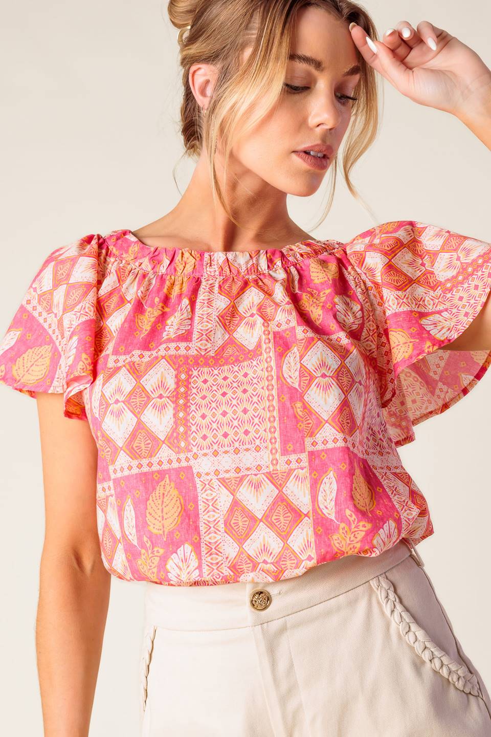 A printed woven top featuring round neckline, flutter sleeve and back neck button closure