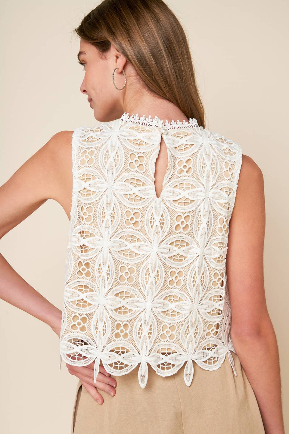 A woven lace top featuring lace trimmed high neckline, sleeve less and back neck button closure